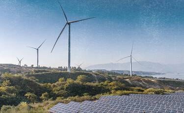 Landscape featuring wind turbines and solar panels under a clear blue sky, representing the brand’s commitment to using renewable energy for manufacturing.
