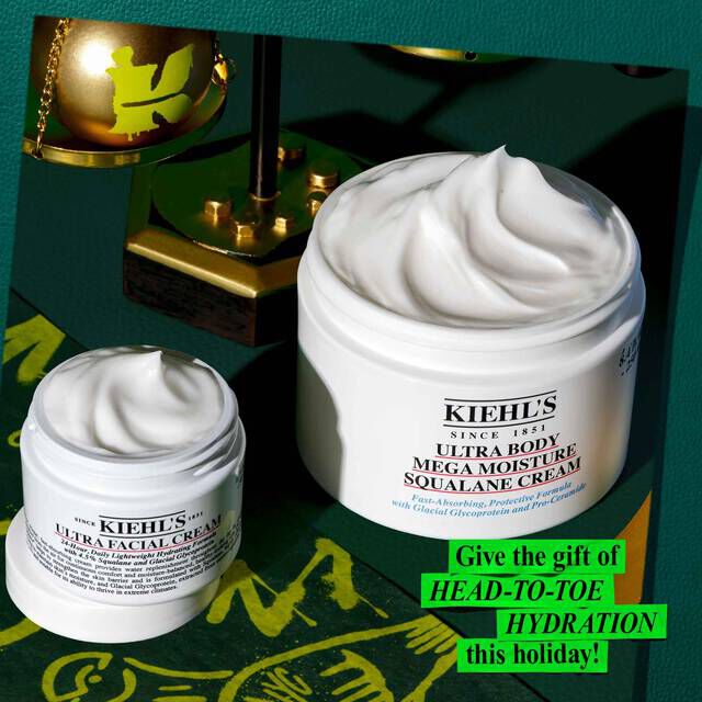 A graphic, set against a dark green background with gold and green accents, features two open white jars with visible swirls of product. The smaller jar is "KIEHL’S ULTRA FACIAL CREAM," and the larger jar is "KIEHL’S ULTRA BODY MEGA MOISTURE SQUALANE CREAM." A gold Christmas ornament with a green "K" logo is in the upper left. In the lower right corner, bright green text reads "Give the gift of HEAD-TO-TOE HYDRATION this holiday!"