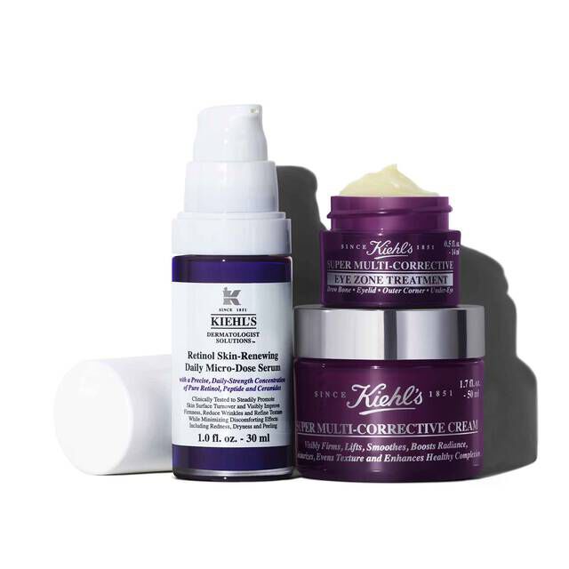 A white and purple bottle of Retinol Skin-Renewing Daily Micro-Dose Serum, a small purple jar of Super Multi-Corrective Eye Zone Treatment, and a larger purple jar of Super Multi-Corrective Cream, and the entire set is casting a shadow on a white background.