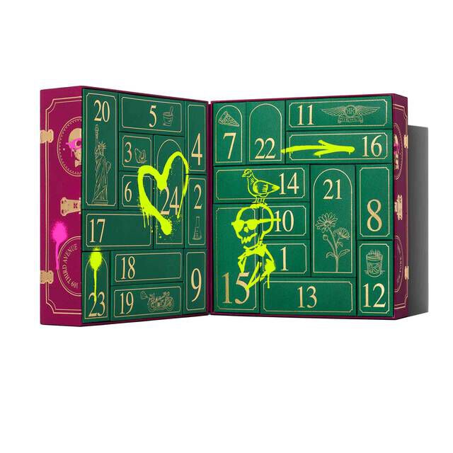 The Kiehl’s Advent Calendar shown open, revealing 24 numbered compartments in green and gold, with playful neon yellow illustrations and festive accents across the interior panels.