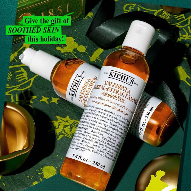 A graphic, set against a festive green and gold background, displays two bottles: "KIEHL'S CALENDULA DEEP CLEANSING FOAMING FACE WASH" and "KIEHL'S CALENDULA HERBAL-EXTRACT TONER," both with clear packaging and amber-colored liquid. The top left corner features a bright green label with the text "Give the gift of SOOTHED SKIN this holiday!"